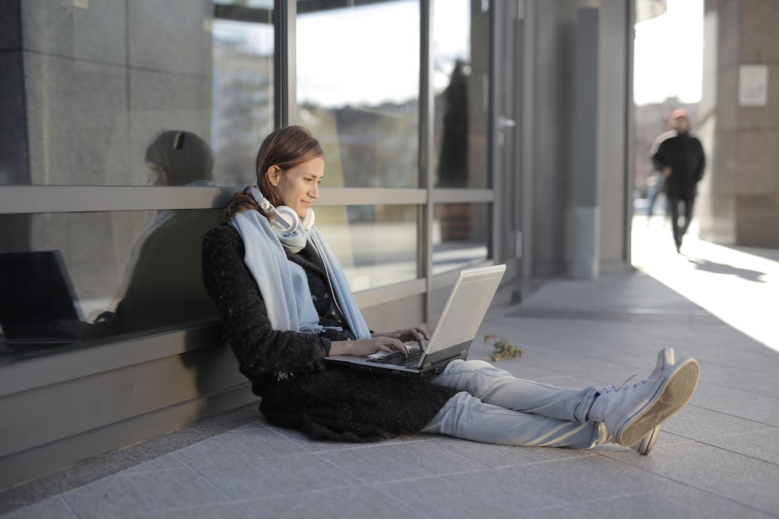 Free Woman in Black Coat and Gray Pants Sitting on Gray Concrete Floor Stock Photo
